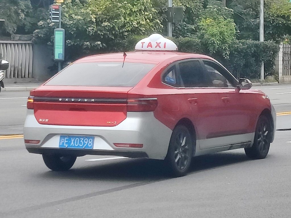 Taxi đỏ bạc chạy trên đường phố Thượng Hải nhìn từ phía sau