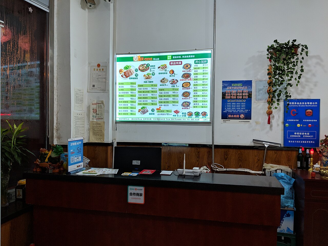 Quầy thu ngân với thực đơn và bảng giấy phép chữ Hán trong một quán thịt heo ở Trung Quốc